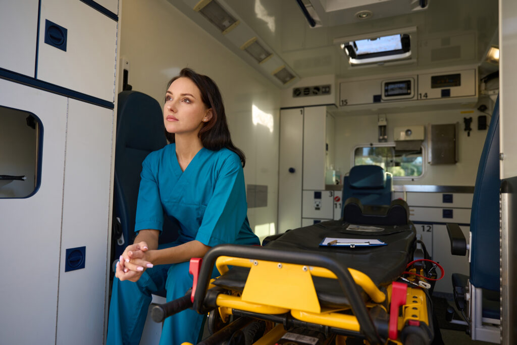 woman in scrubs sitting inside of ambulance 2026 03 19 22 07 20 utc